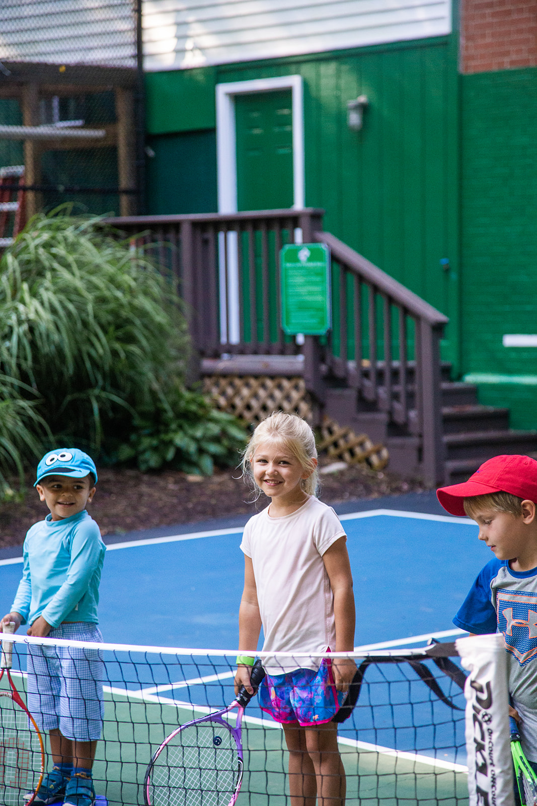 Photo of three young tennis players standing by the net at Langley Swim and Tennis Club