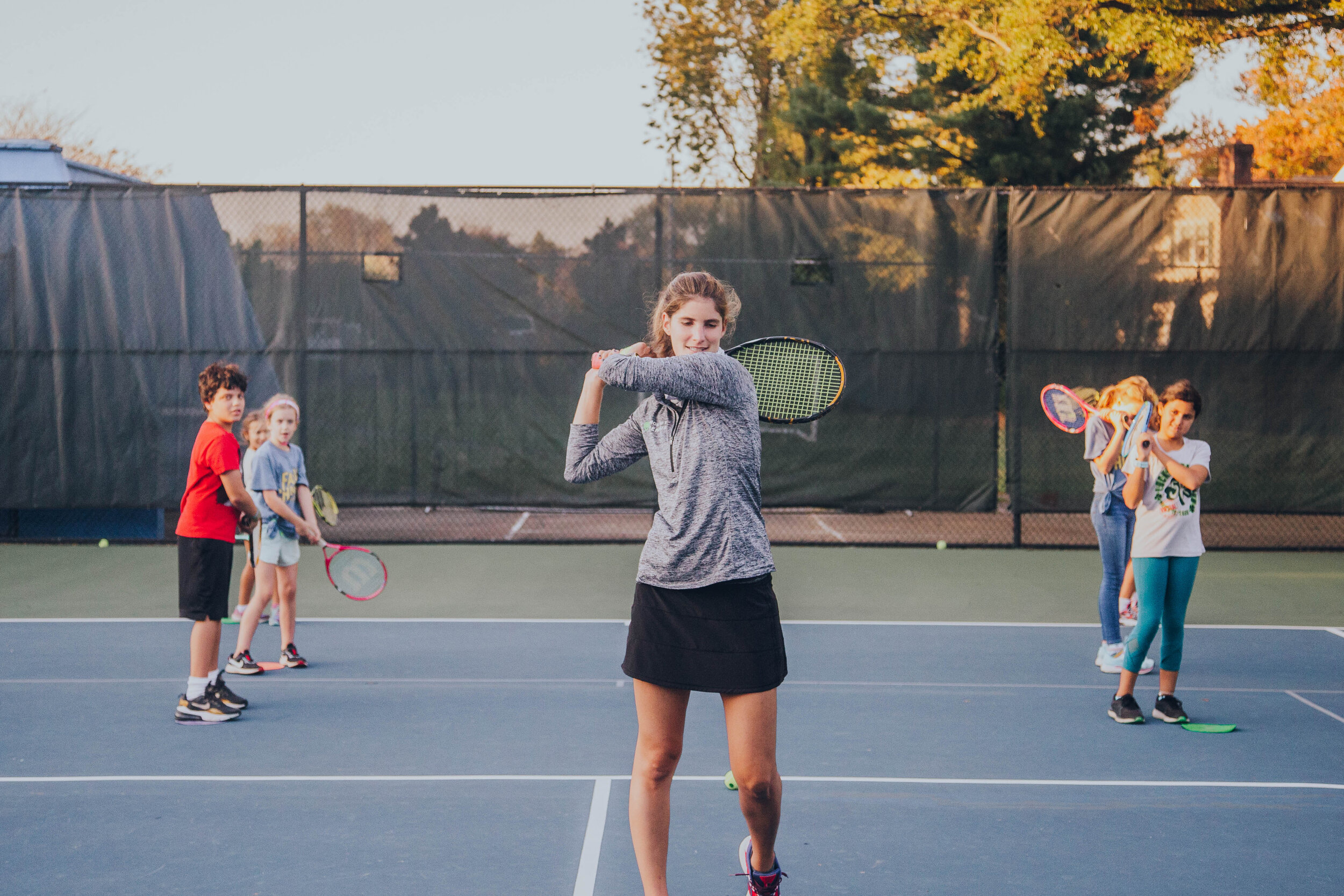 Photo of five young people participating in outdoor YMCA tennis lessons