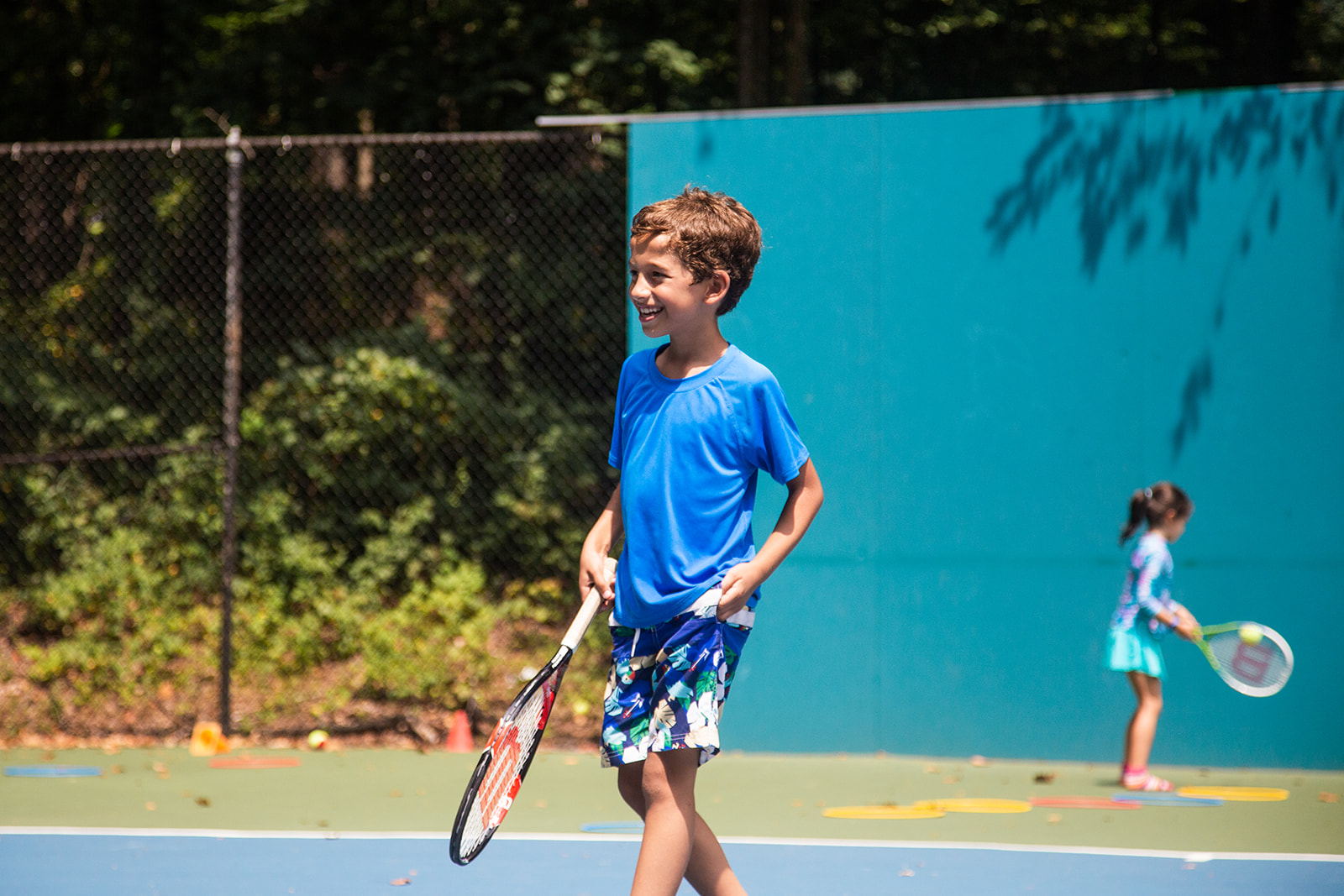 Photo of a boy in a blue shirt holding a tennis racket, taking youth tennis program at Old Georgetown Tennis Club